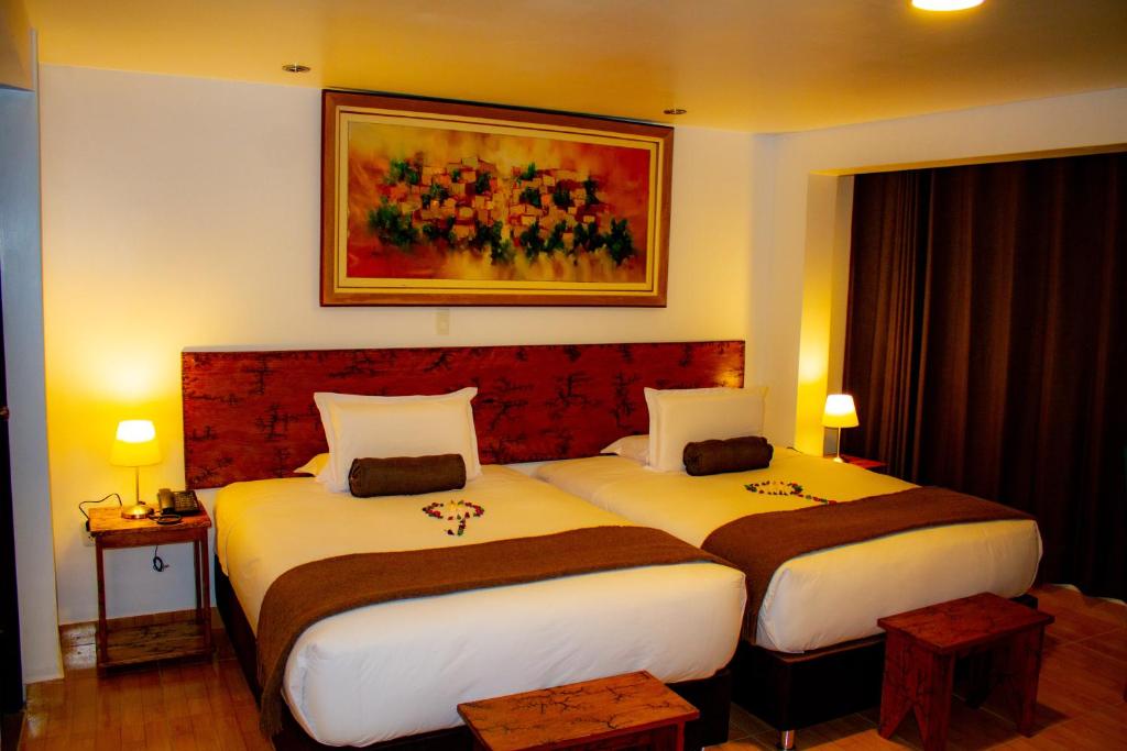 a hotel room with two beds and a painting on the wall at Hotel Tara Machupicchu in Machu Picchu