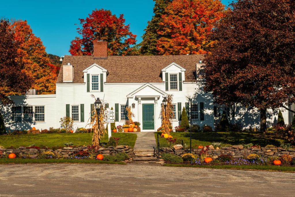 une maison blanche avec des citrouilles dans la cour dans l'établissement The Hermitage Inn Vermont, à West Dover