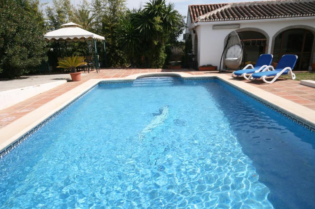 ein Pool mit zwei blauen Stühlen und ein Haus in der Unterkunft Casacool in Málaga
