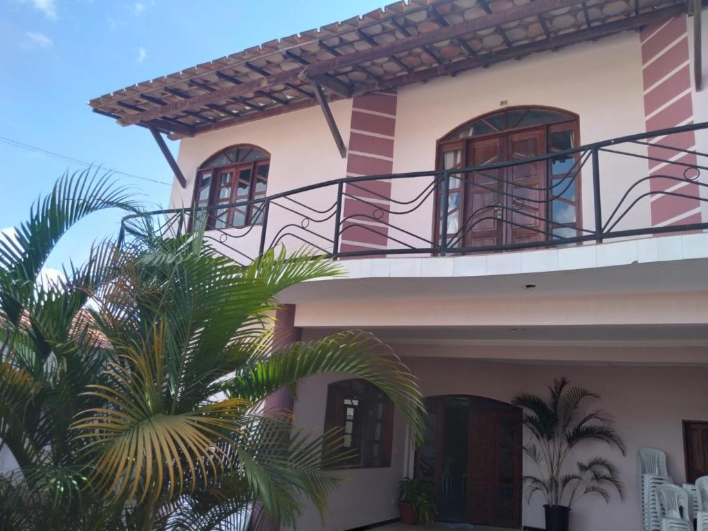 a house with a balcony and palm trees in front of it at Pousada Emanuell in Ibicoara