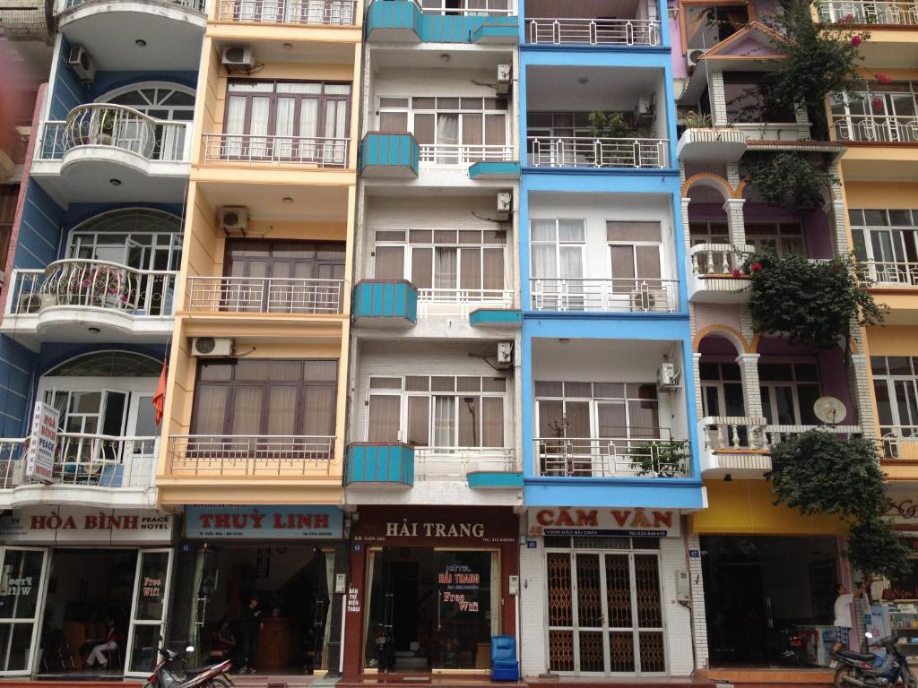 un edificio alto con balcones azules en una calle de la ciudad en Hai Trang Hotel, en Ha Long