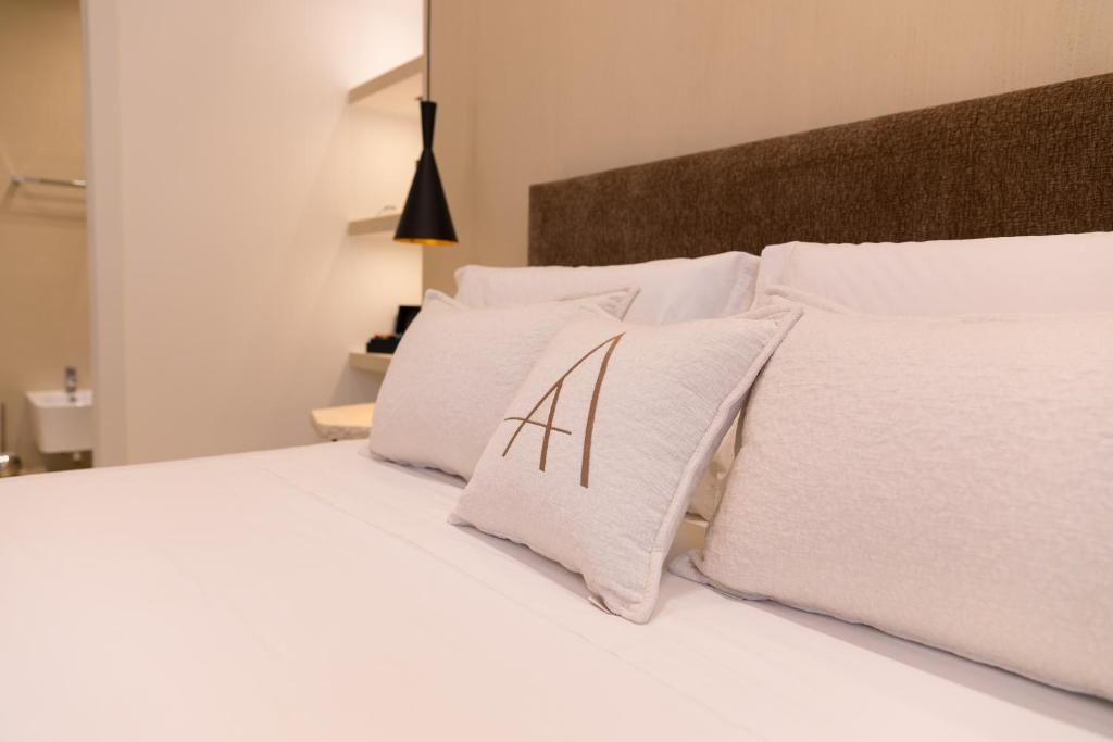 een wit bed met witte kussens erop bij Double A Luxury Room in Olbia