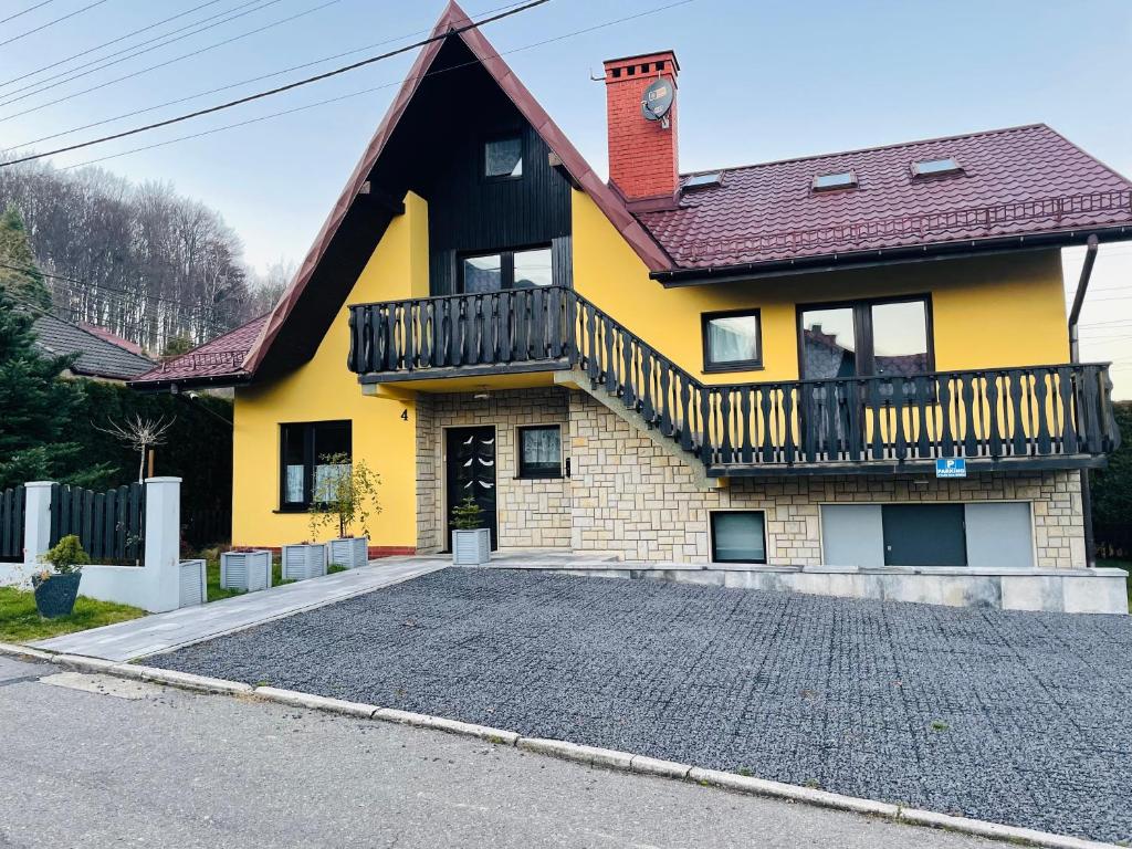 a yellow house with a balcony and a driveway at Domek pod Czantorią in Ustroń