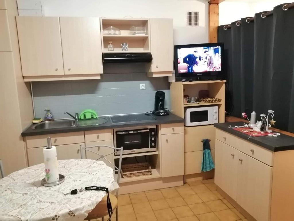 une petite cuisine avec une table et une télévision dans l'établissement Appartement T2 RDC centre Vitré 35500, à Vitré