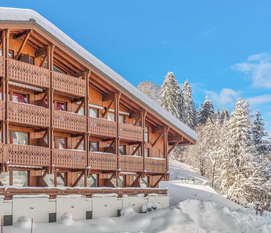 um grande edifício de madeira com neve no chão em Megève - Appartement 2 chambres - Proche Centre et Pistes - Wifi Netflix - Parking em Megève