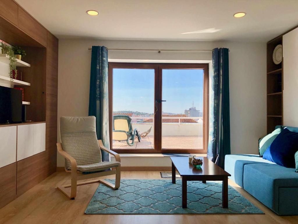 a living room with a blue couch and a window at Imowemo OVAR Multifuncional penthouse studios in Ovar