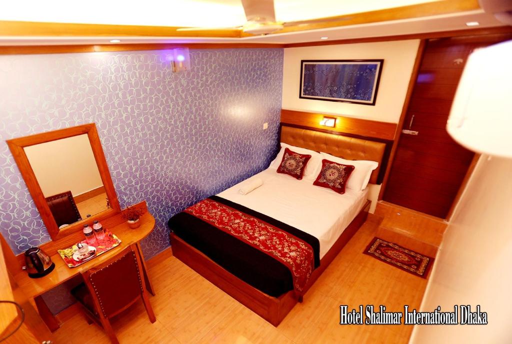 een kleine slaapkamer met een bed en een spiegel bij Hotel Shalimar Motijheel - Centre of City in Dhaka