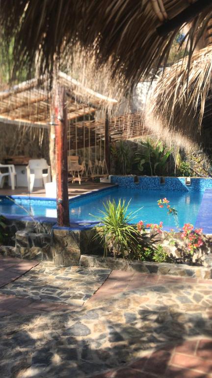 um resort com uma piscina e um telhado de palha em Villa del Mar em Zipolite