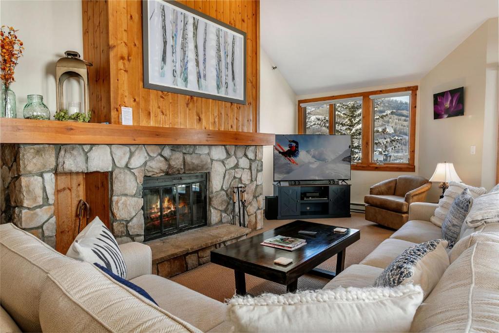 a living room with a stone fireplace and a television at 326 Kiva Condo access to Ski in Out in Avon