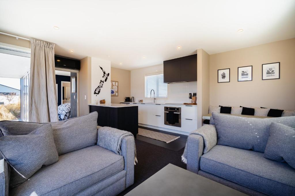 a living room with two couches and a kitchen at Mountain Vista Retreat - Apartment 1 in Twizel