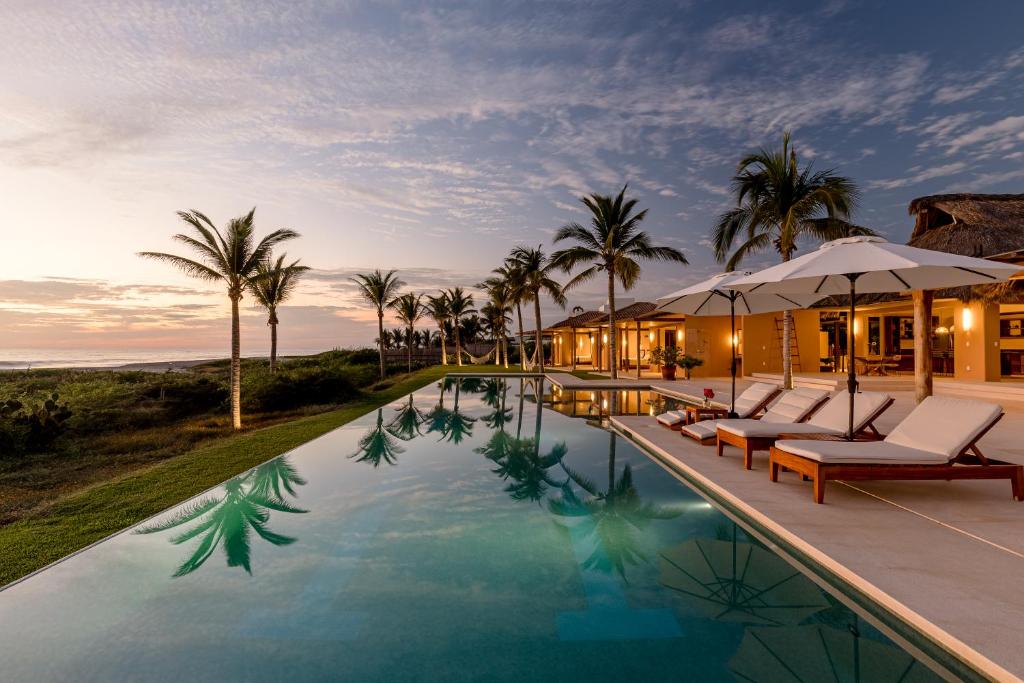 una villa con piscina y palmeras en Casa Constantia Beach Front Villa, en Puerto Escondido