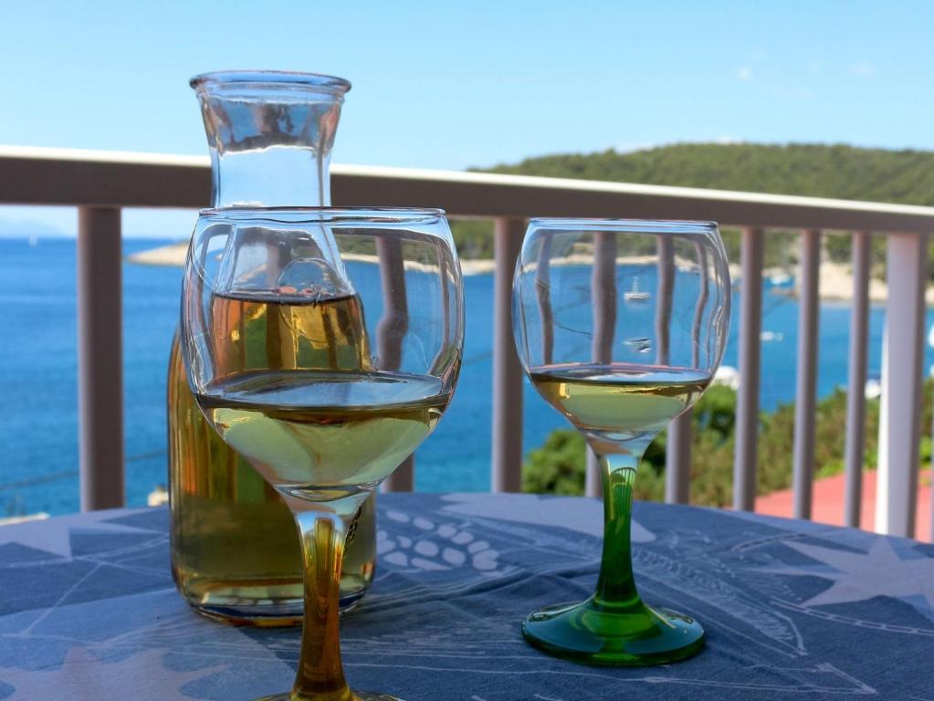 dos vasos de vino blanco sentados en una mesa en Apt and rooms Marlene - 50 m from sea, en Milna
