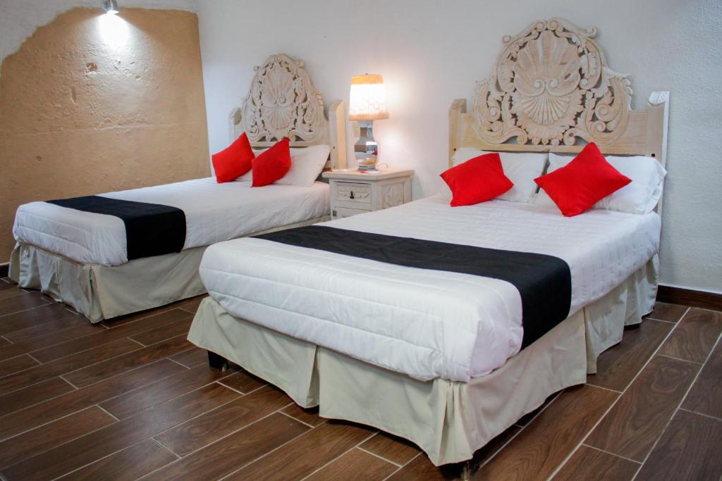two beds in a hotel room with red pillows at Hotel Boutique Don Porfirio in Apaseo el Grande