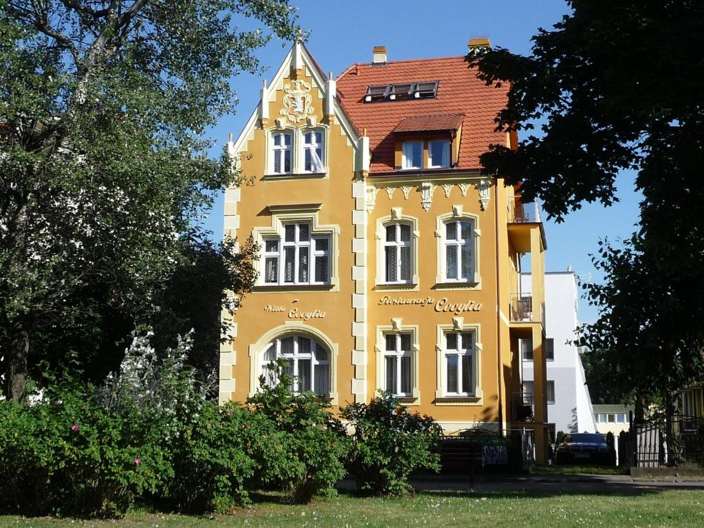 un edificio amarillo con una torre de reloj. en Willa Cecylia, en Międzyzdroje
