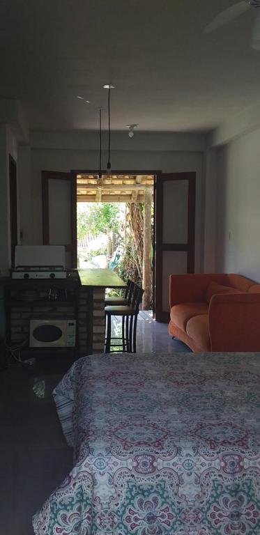a bedroom with a bed and a living room with a couch at Chalé Verde in Barra de Ibiraquera