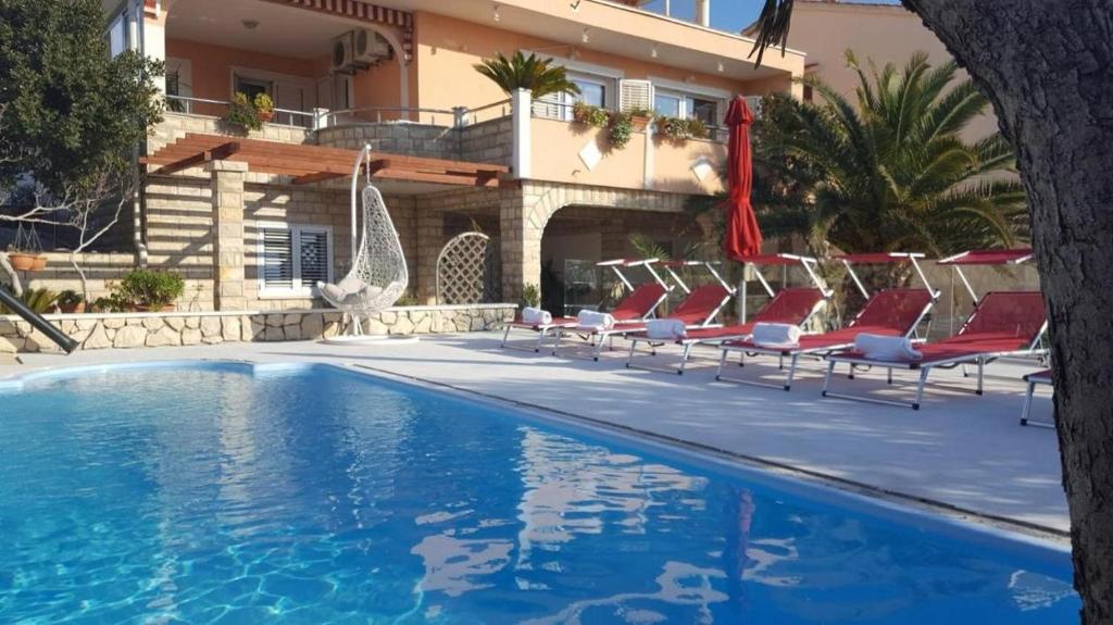 - une piscine avec des chaises longues et un bâtiment dans l'établissement Apartments and rooms Cherry - relax & chill by the pool, à Novalja