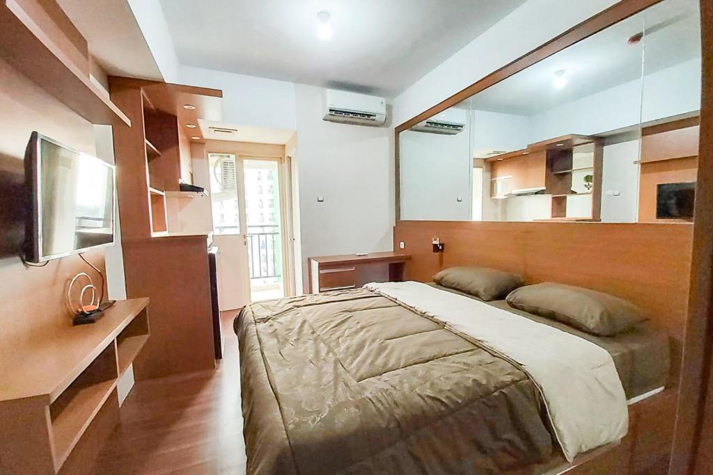 - une chambre avec un grand lit et un miroir dans l'établissement RedLiving Apartemen Green Lake View Ciputat - Juragan Rooms Tower B with Fast Wifi, à Pondokcabe Hilir