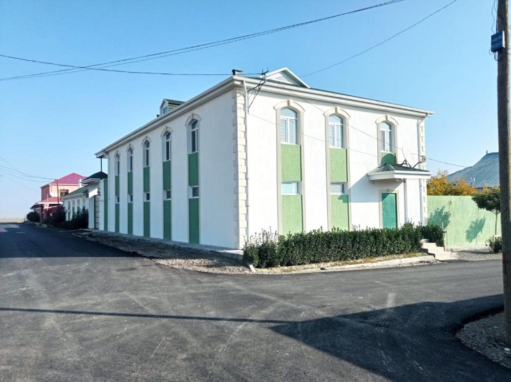 ein weißes und grünes Gebäude an der Straßenseite in der Unterkunft Bizim Ev hostel in Naftalan