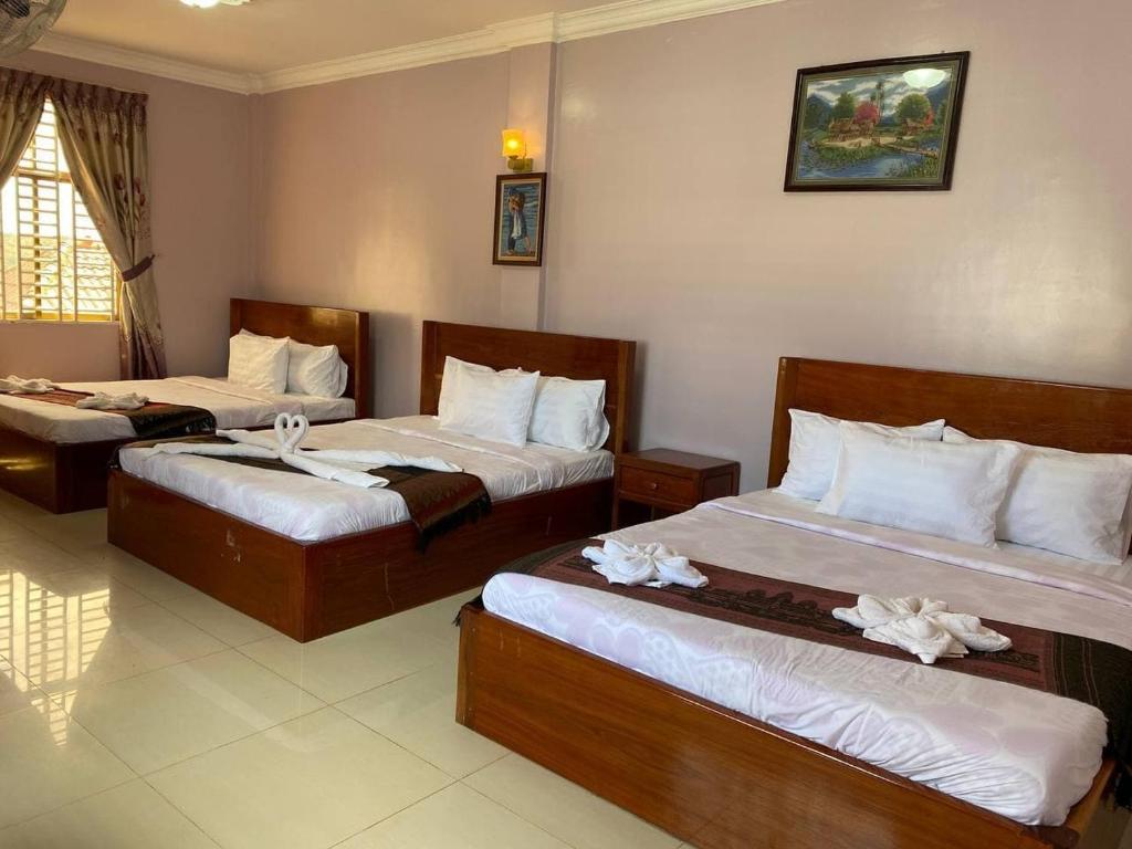 Habitación de hotel con 2 camas con sábanas blancas en Avocado Guesthouse en Sen Monorom
