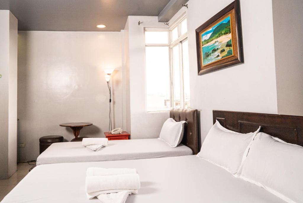 um quarto de hotel com duas camas e uma janela em GETZ HOTEL MANILA em Manila