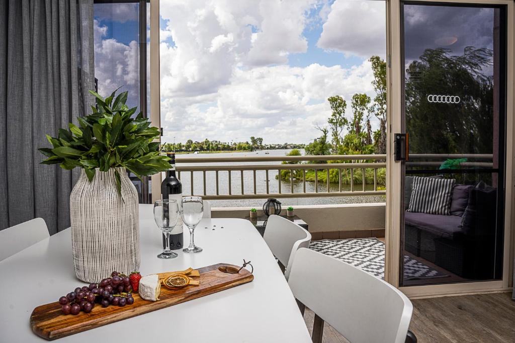 a white table with a vase of grapes and wine glasses at Mulwala Lakeside Apartment in Mulwala