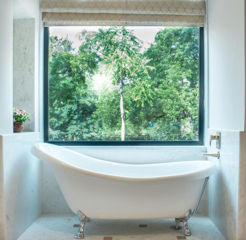 uma banheira na casa de banho com uma janela em Brij Nest, Jaipur - An All Suite Boutique Hotel em Jaipur
