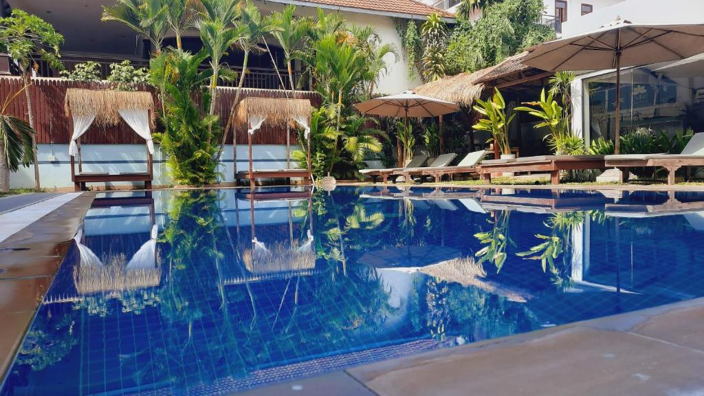 a swimming pool with chairs and umbrellas at a resort at Babel Siem Reap Guesthouse in Siem Reap