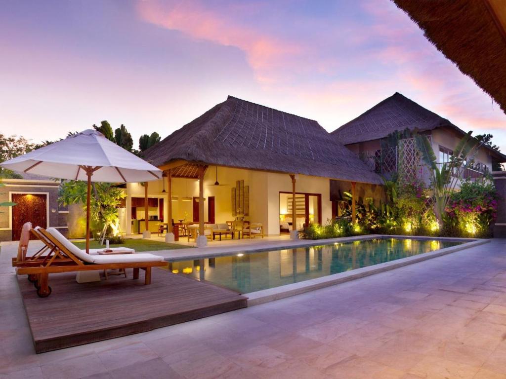 a house with a pool and a balcony overlooking the water at Impiana Private Villas Seminyak - CHSE Certified in Seminyak