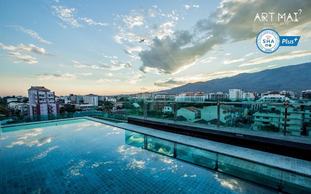 a swimming pool on the roof of a building with a city at Art Mai Gallery Nimman Hotel Chiang Mai - SHA Plus in Chiang Mai