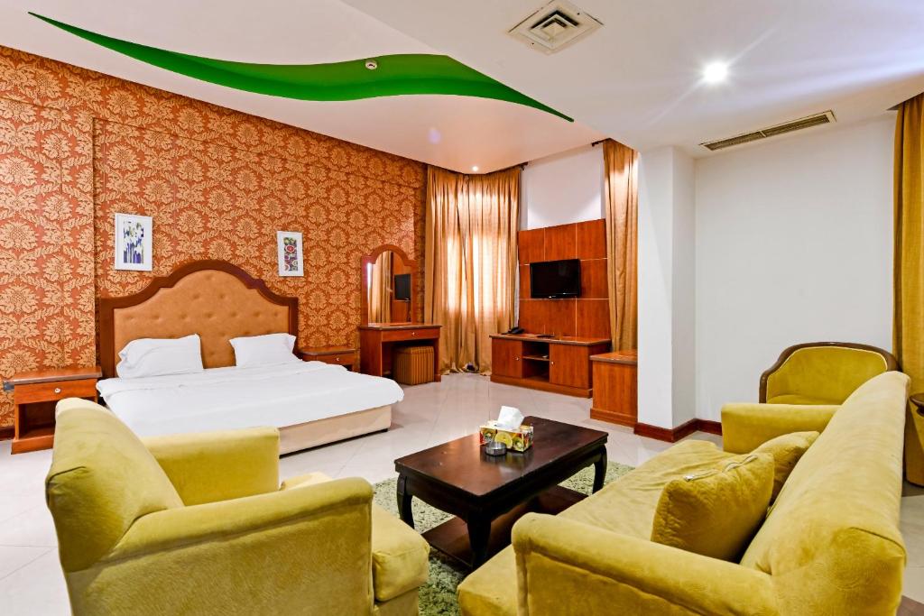 a hotel room with a bed and a couch and chairs at OYO 118 Revira Hotel in Manama