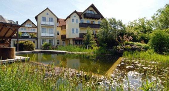 ein großes Haus mit einem Teich davor in der Unterkunft Hotel Wiesend in Kulmain