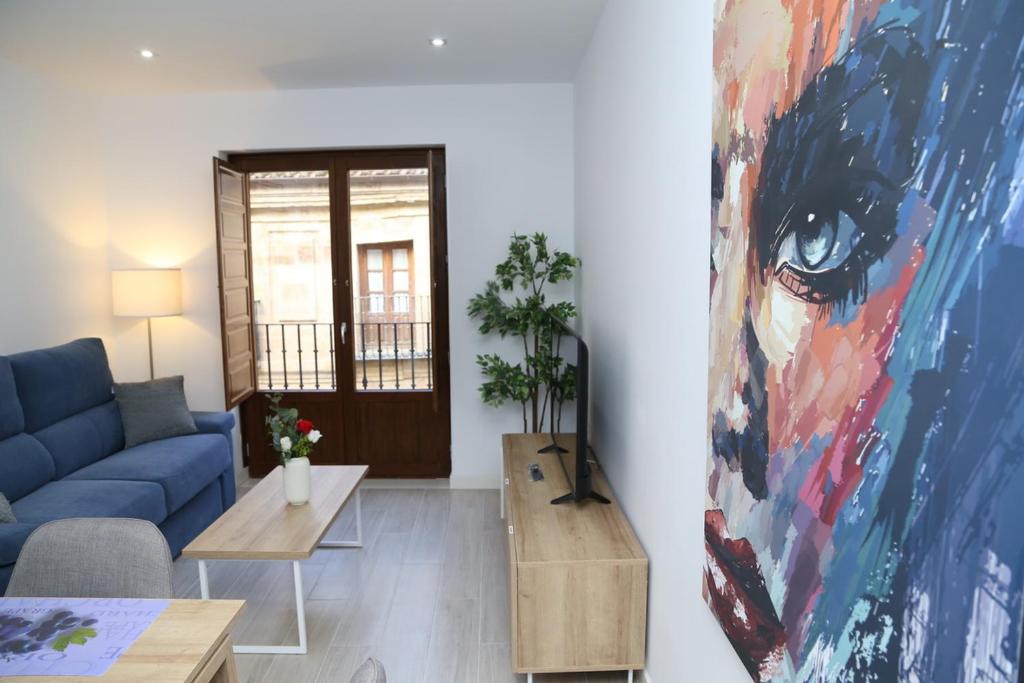 ein Wohnzimmer mit einem blauen Sofa und einem Gemälde in der Unterkunft Piso Plaza Mercado 2,3 in Salamanca