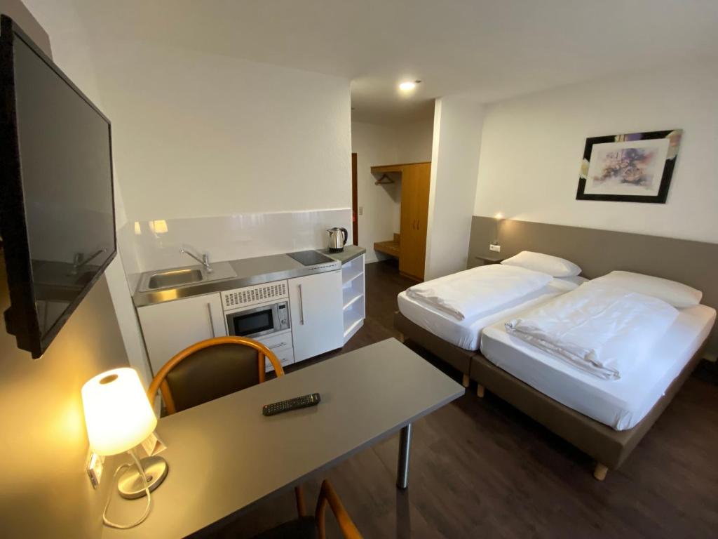 a hotel room with two beds and a table at Hotel am Schillerplatz in Pleidelsheim