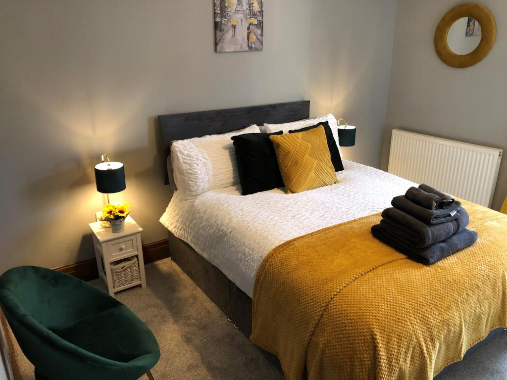 a bedroom with a bed and a green chair at Moss Cottage in Willaston