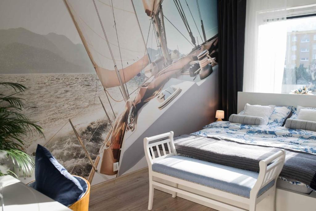 Apartament HAMPTONS Gdynia في غدينيا: غرفة نوم بسرير ولوحة قارب شراعي