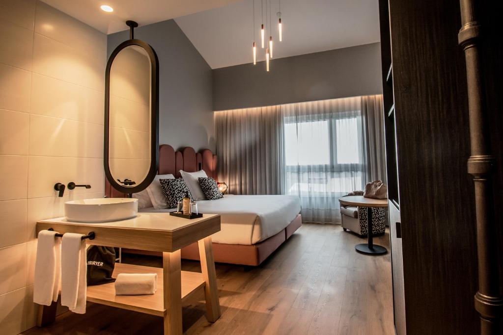 a bedroom with a bed and a sink and a mirror at Mercure Lugo Centro in Lugo