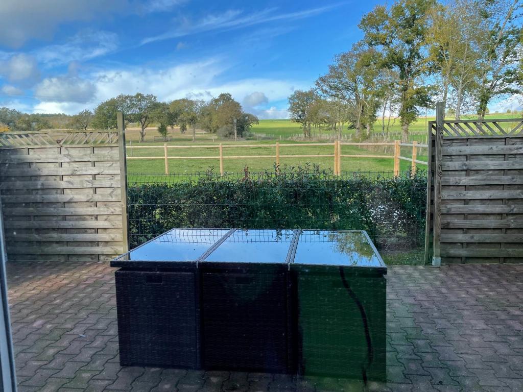 a table in front of a fence with a field at Le Gîte de la Vilaine in Sainte-Anne-sur-Vilaine