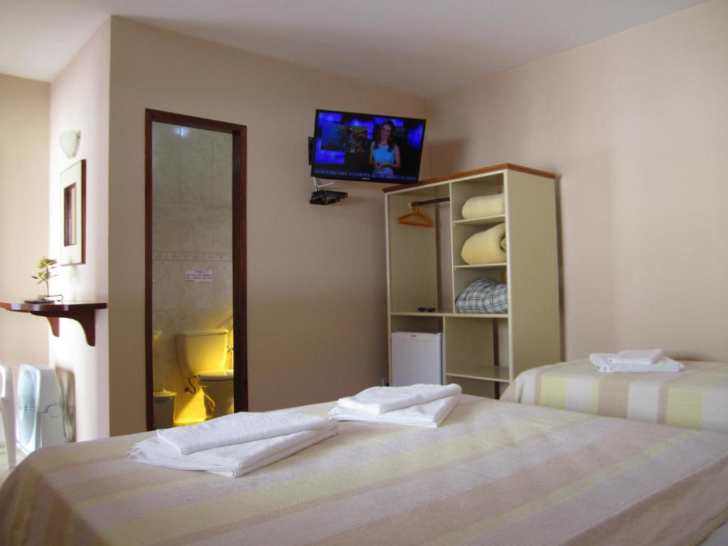 a bedroom with two beds and a tv on the wall at Pousada do Alferes in Paty do Alferes