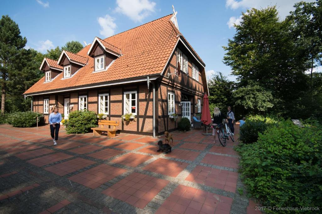 a woman walking a dog in front of a house at Ferienhaus Viebrock 