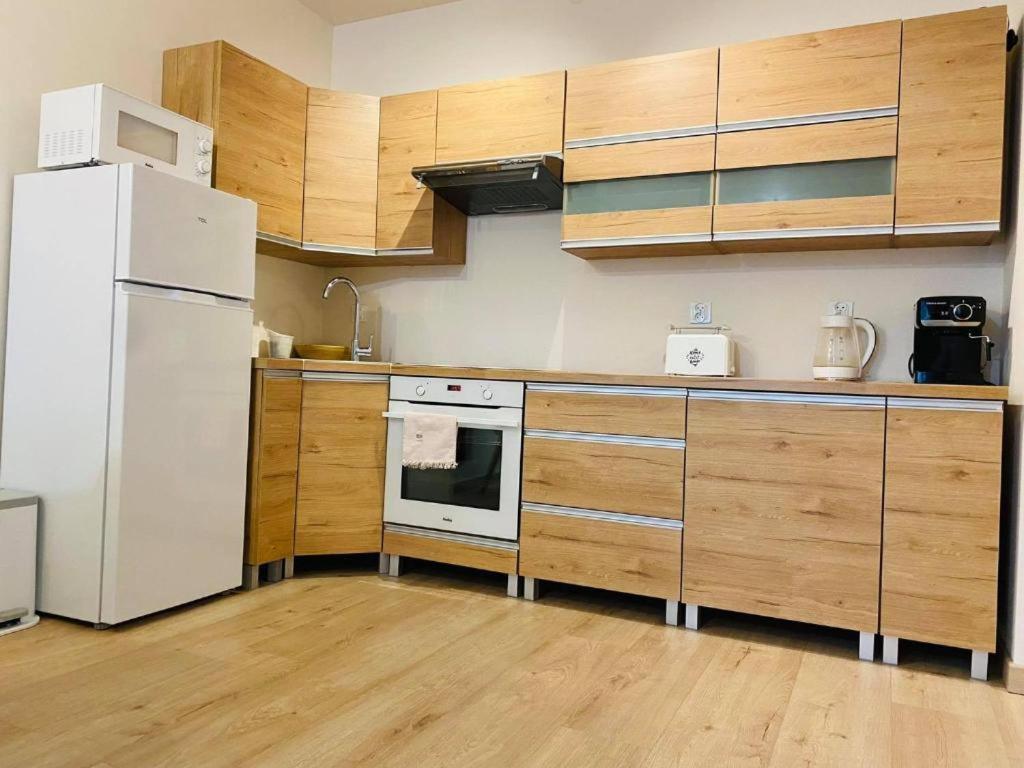 a kitchen with a white refrigerator and wooden cabinets at Apartament Przytulny in Kołobrzeg