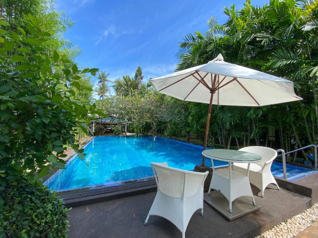 uma mesa e cadeiras com um guarda-sol ao lado de uma piscina em Lokal Phuket "Former K-Hotel" - SHA Extra Plus em Patong Beach