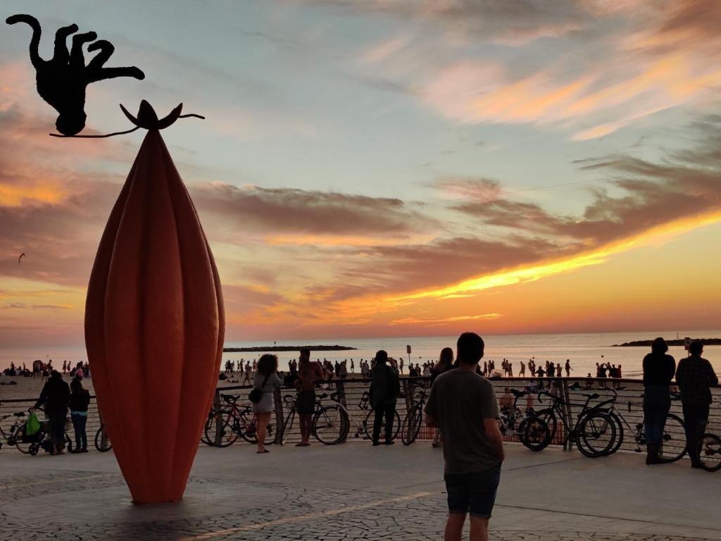 un gruppo di persone in piedi sulla spiaggia con una tavola da surf di Central Stay TLV Beachfront a Tel Aviv