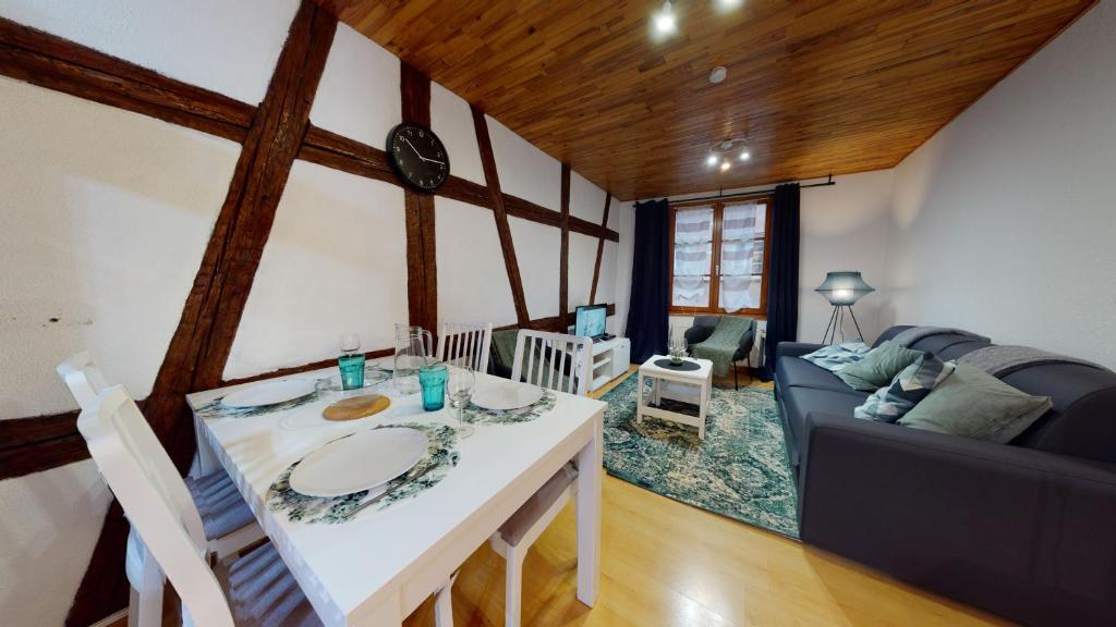 uma sala de estar com uma mesa e um sofá em Le Petit Thierenbach em Colmar