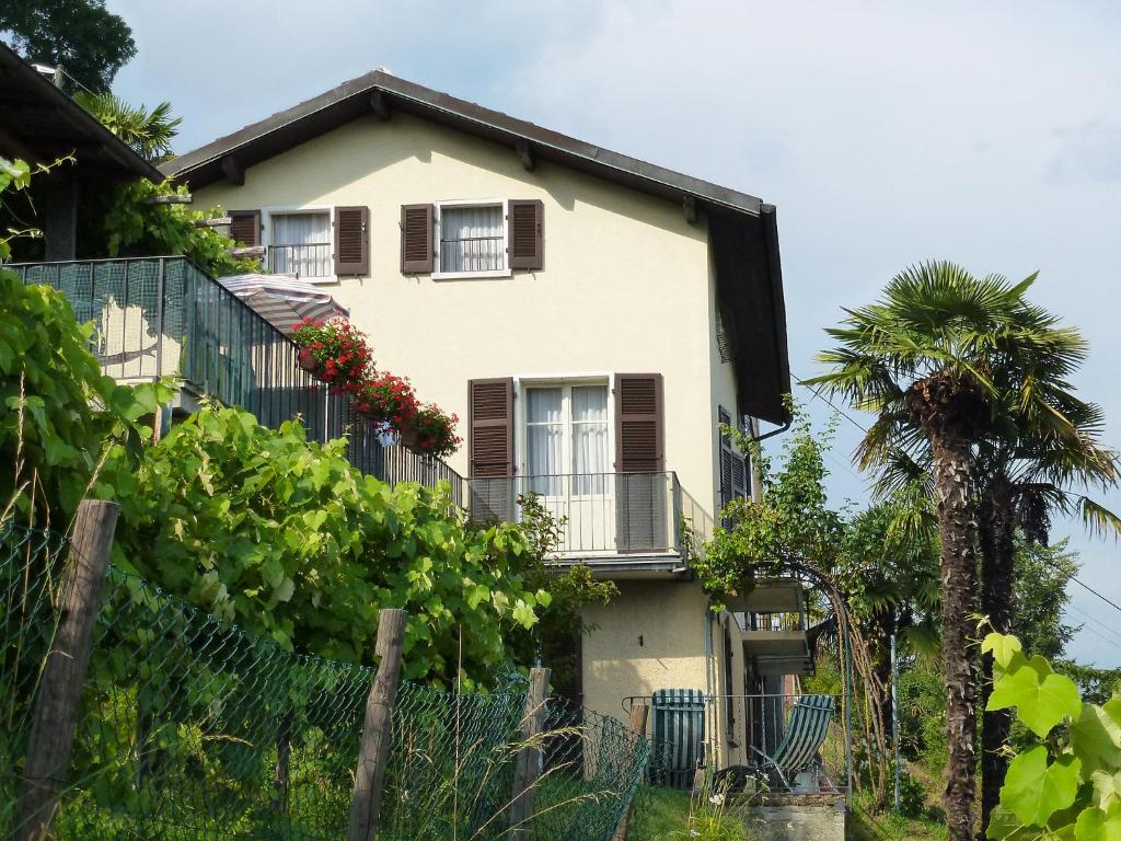 ein weißes Haus mit einem Balkon und einer Palme in der Unterkunft Apartment al Ronchetto by Interhome in Carona