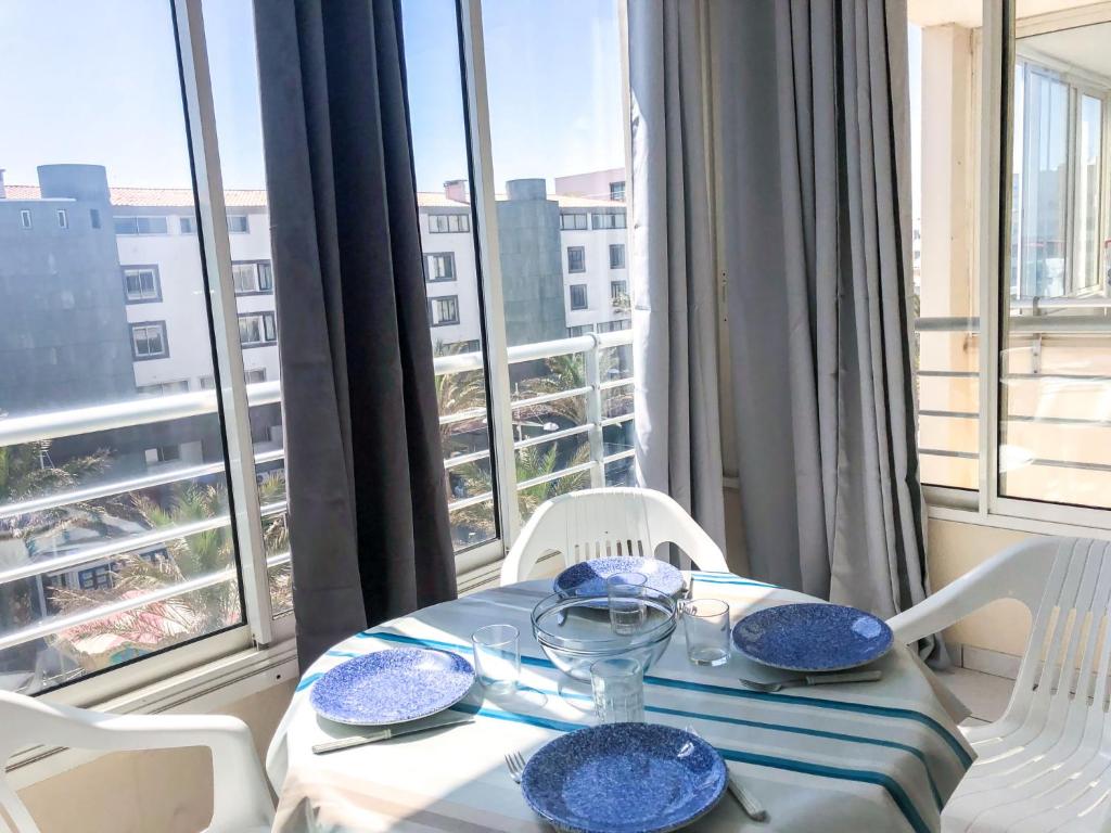 d'une table et de chaises avec vue sur une fenêtre. dans l'établissement Apartment La Palme d'Or-16 by Interhome, au Cap d'Agde