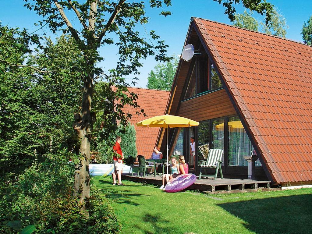 a group of people sitting under an umbrella outside of a house at Holiday Home Winnetou by Interhome in Machtlos