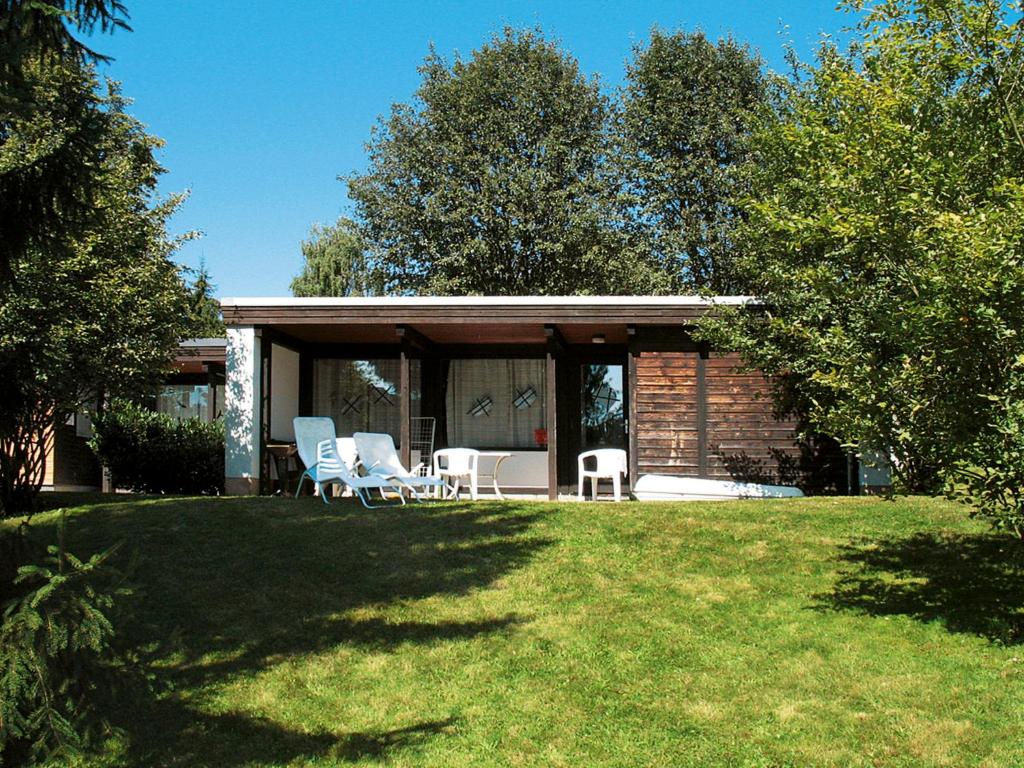 uma casa com duas cadeiras e um alpendre com árvores em Holiday Home Jägerwiesen - WAH104 by Interhome em Waldkirchen