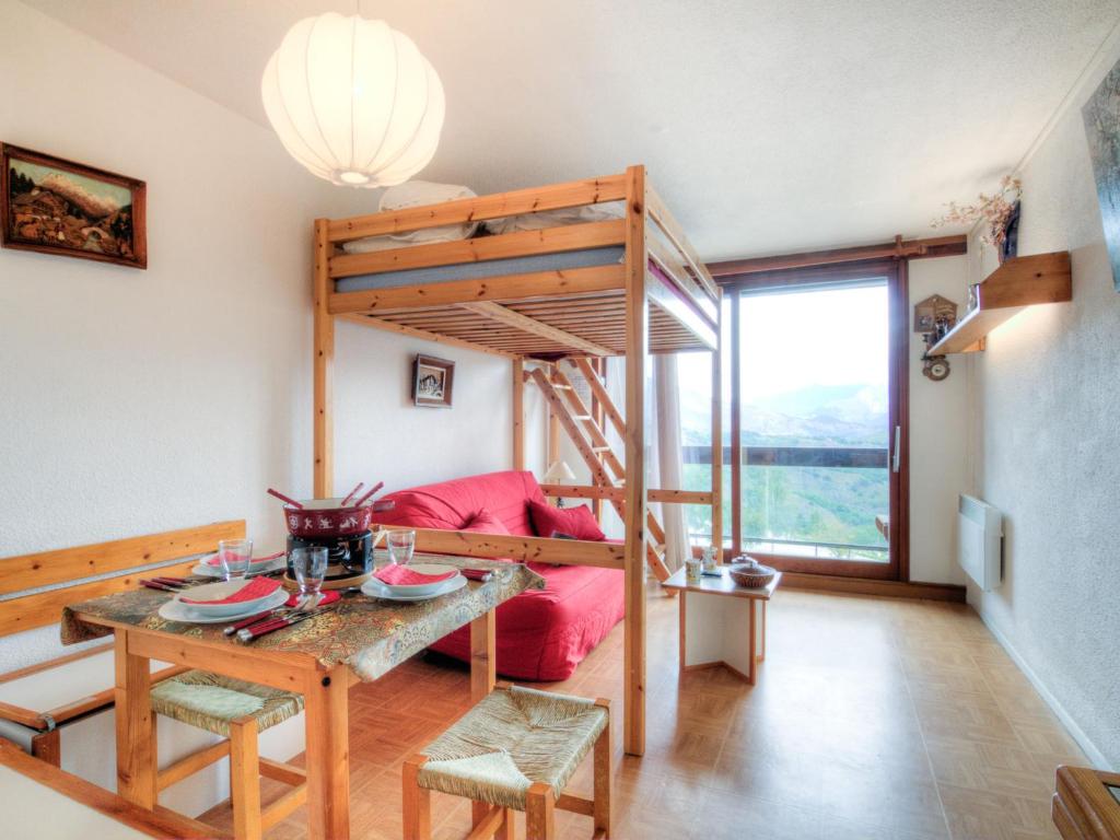 Sala de estar con cama elevada y mesa en Apartment Pegase Phenix-55, en Le Corbier