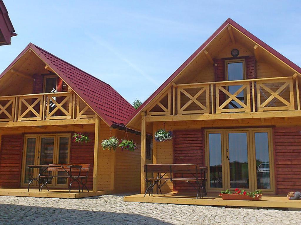 a wooden house with chairs and tables in front of it at Holiday Home Villa Amber Gąski-2 in Gąski