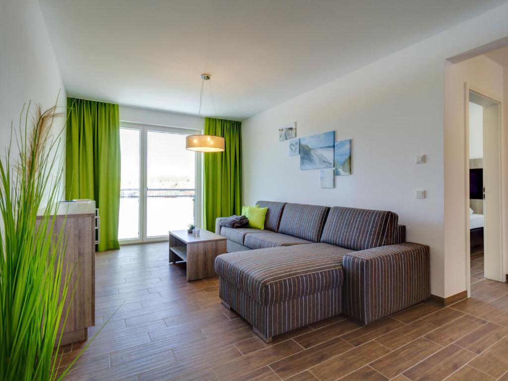 een woonkamer met een bank en groene gordijnen bij Apartment Seglerhütte by Interhome in Großpösna